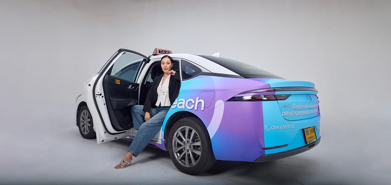 Woman stepping out of a MotionReach wrapped EV taxi