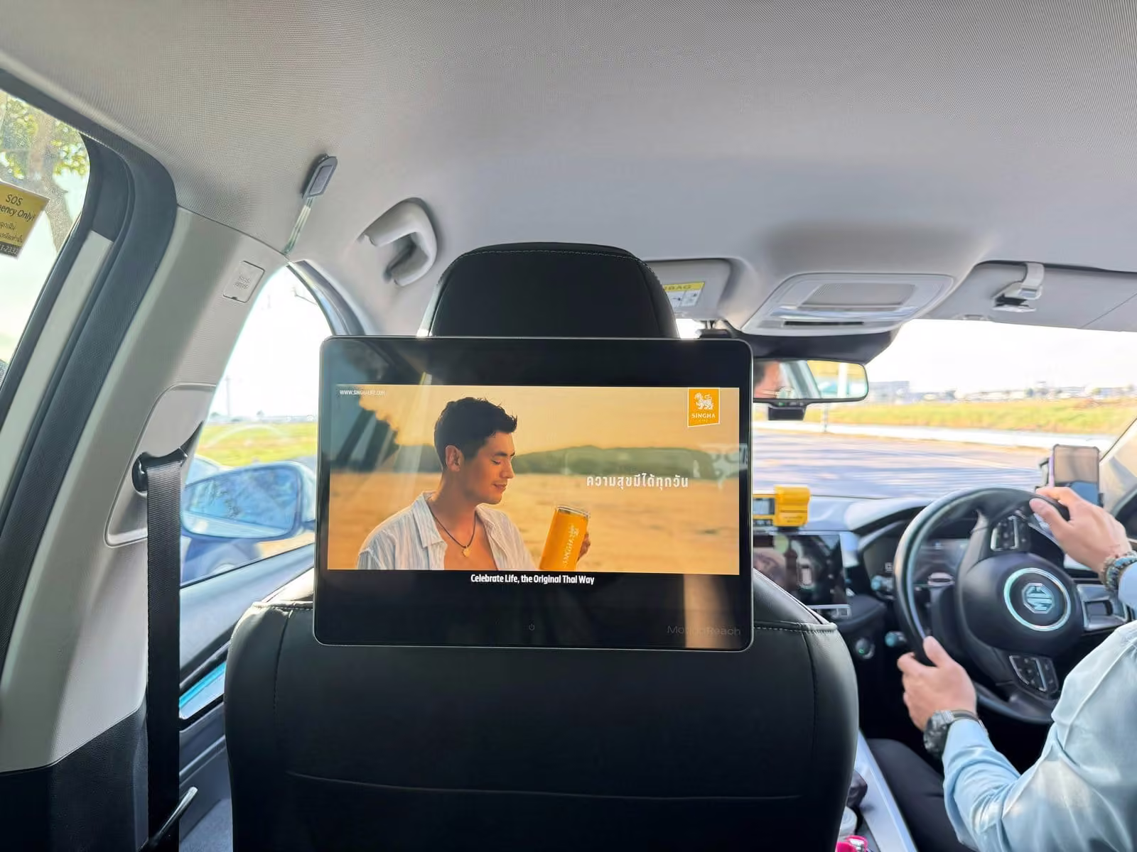 Digital screen on a taxi seat headrest playing a video ad while the taxi is moving, an example of moving DOOH