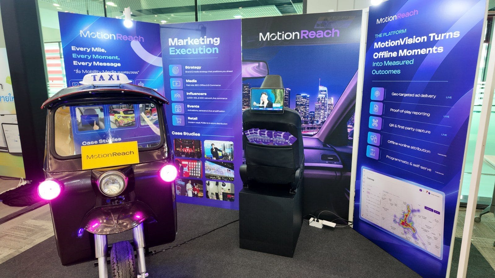 MotionReach booth at Marketing Conference 2026 with a branded tuk-tuk, a taxi seat with a digital screen and MotionVision panels