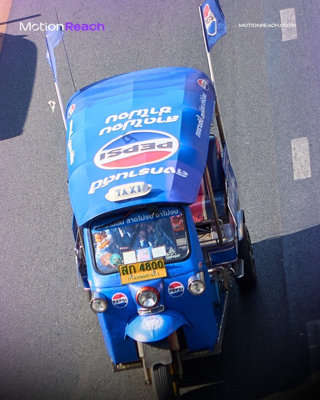 Aerial view of a Pepsi-wrapped tuk-tuk on a Bangkok road