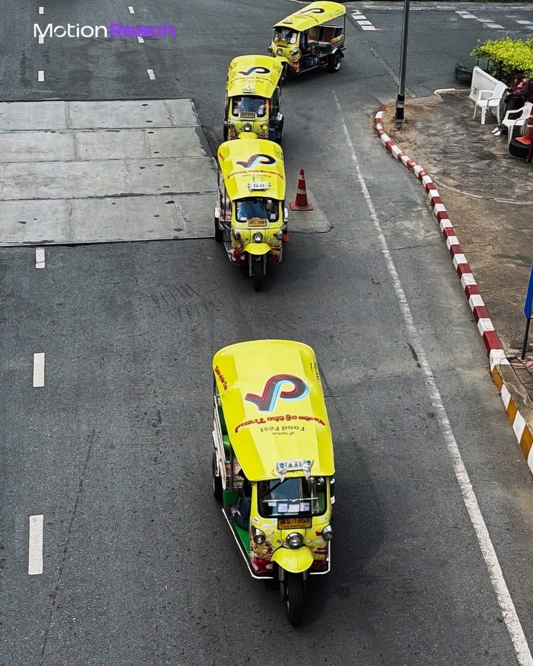 Aerial view of a convoy of TikTok Food Fest wrapped tuk-tuks on a Bangkok road